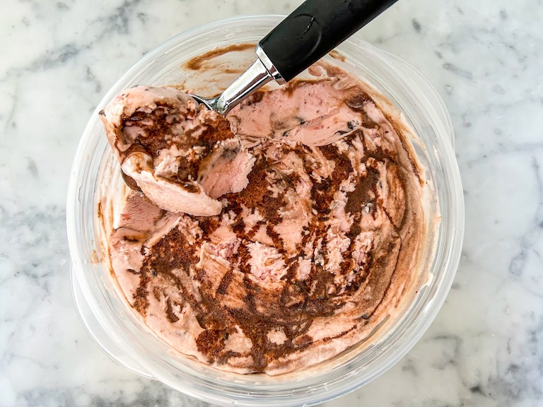 Ice cream scoop in a container of chocolate strawberry ice cream