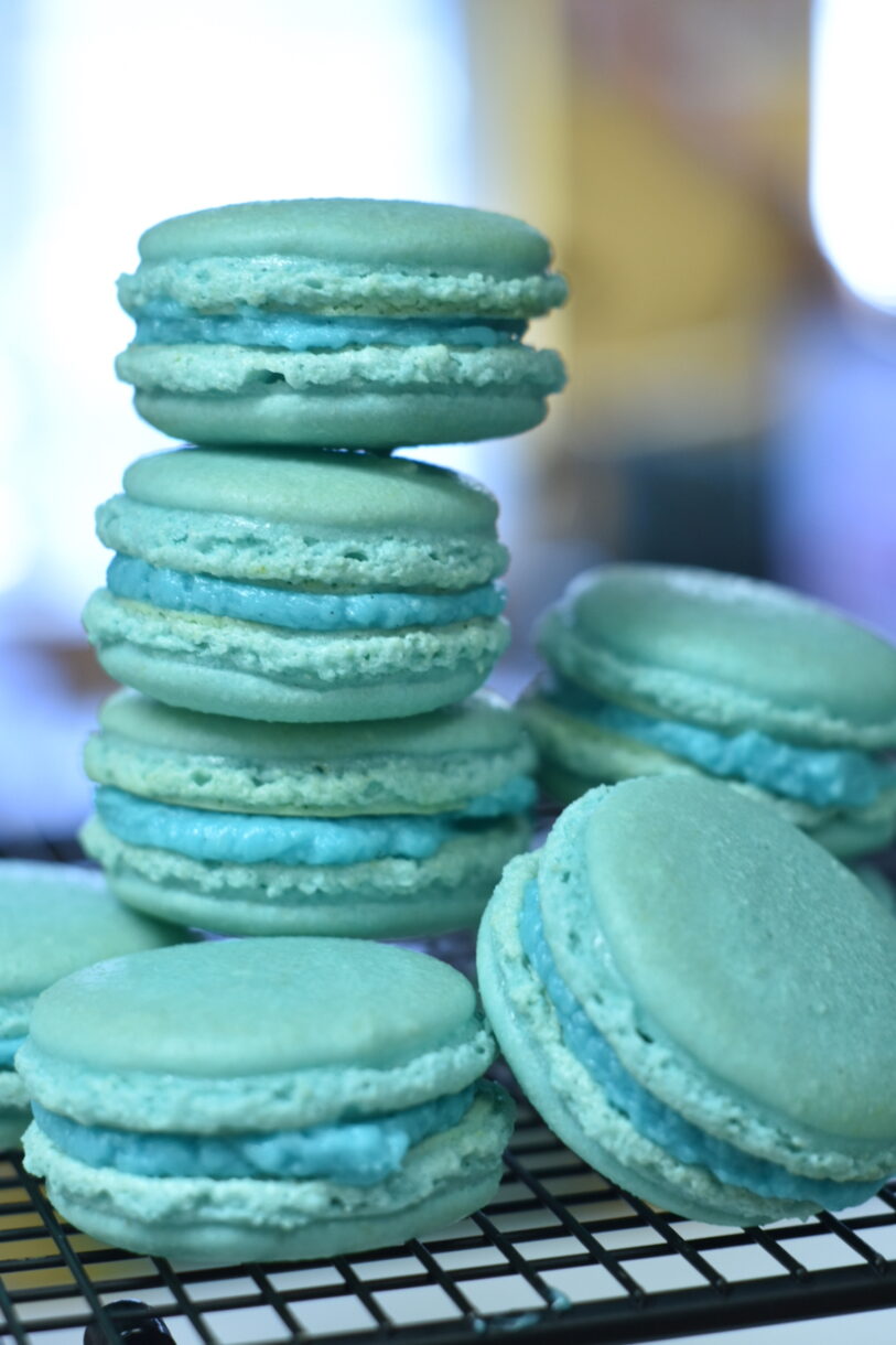 Blue macarons stacked on a wire rack