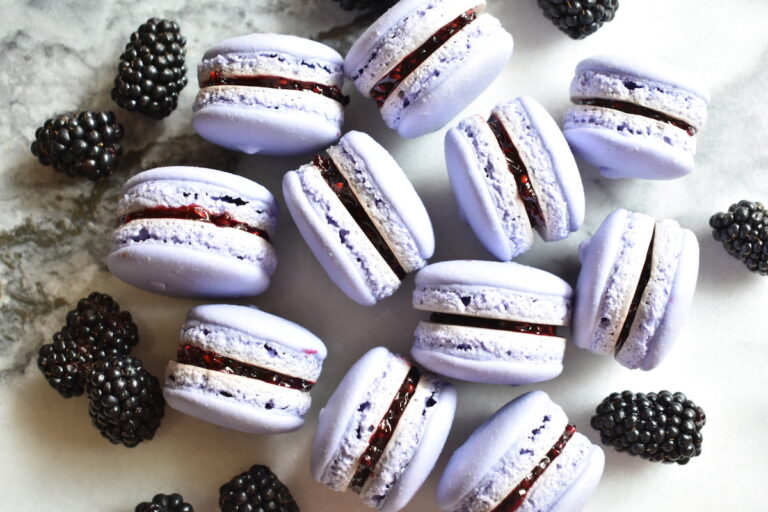 Macarons with blackberry jam and fresh blackberries on a marble countertop