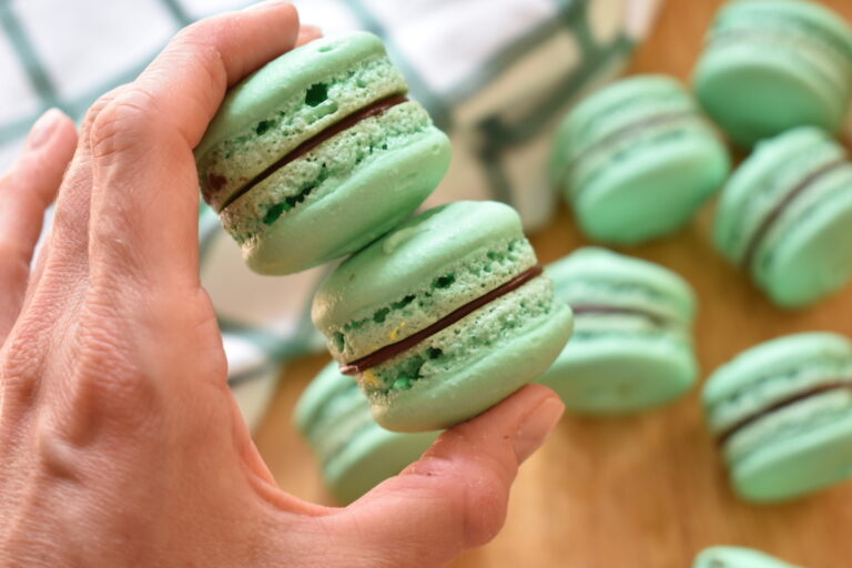 Hand holding two mint green macarons 