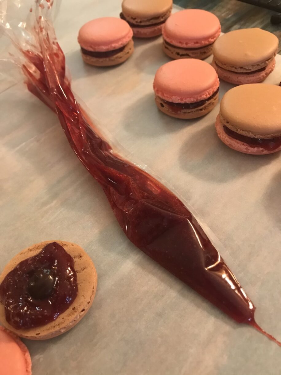 Strawberry chocolate macarons and a piping bag of jam
