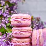 Stack of pink macarons surrounded by purple flowers