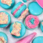 Pop rocks macarons with bright blue shells and a tube of pink frosting