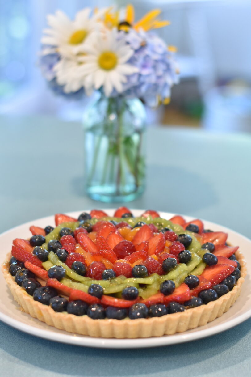 Fruit tart on a table with a vase of flowers