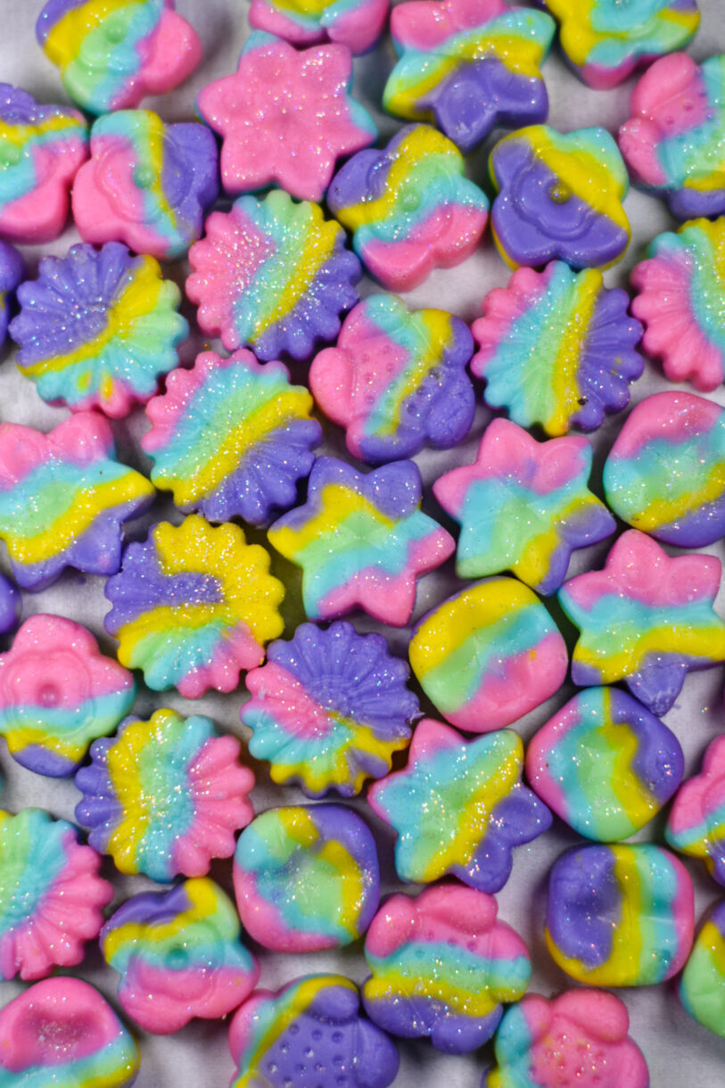 Rainbow cream cheese mints on a white surface