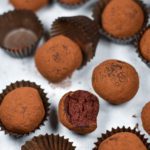 Chocolate beet truffles and truffle cups on white background