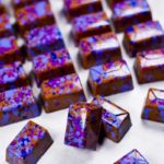 Shiny rectangular chocolate bon bons with purple cocoa butter