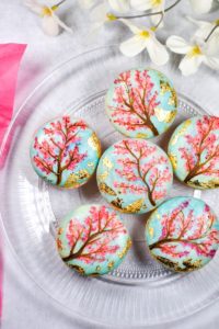 Food photograph of a plate of painted cherry blossom macarons