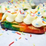 Rainbow eclairs with piping and sprinkles