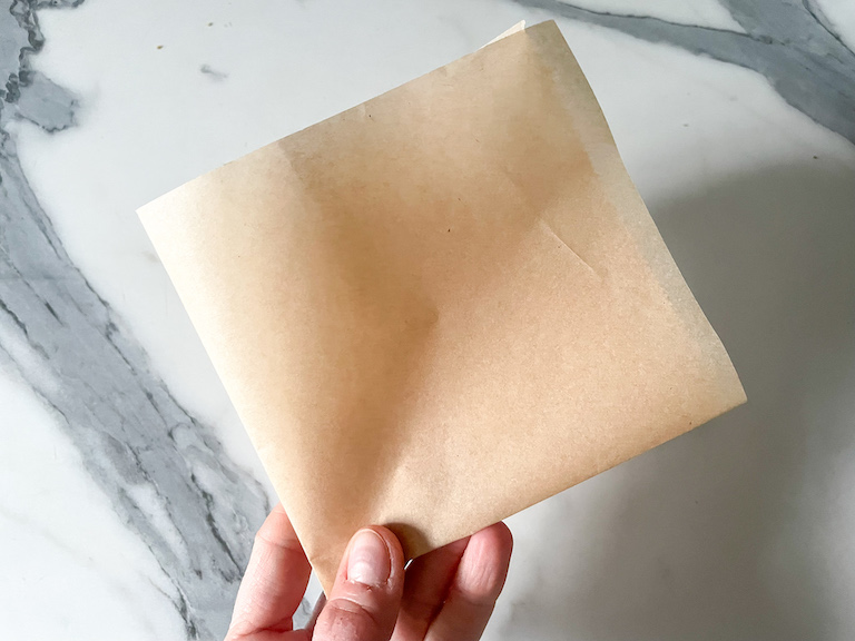 Hand holding a square of baking parchment