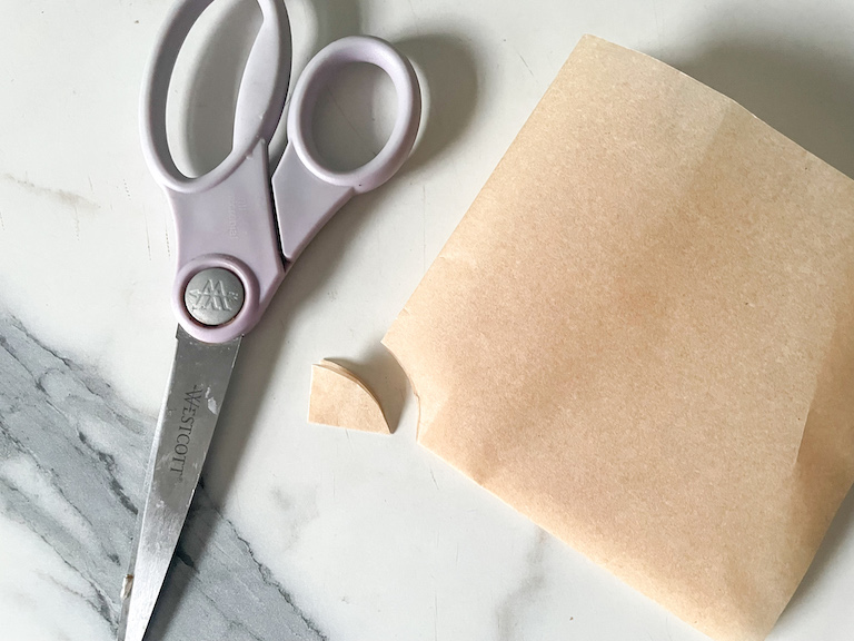 Scissors and a square of parchment with the corner snipped