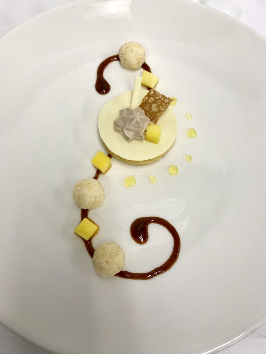 Mock exam plated dessert featuring piped caramel, tempered white chocolate, and mango