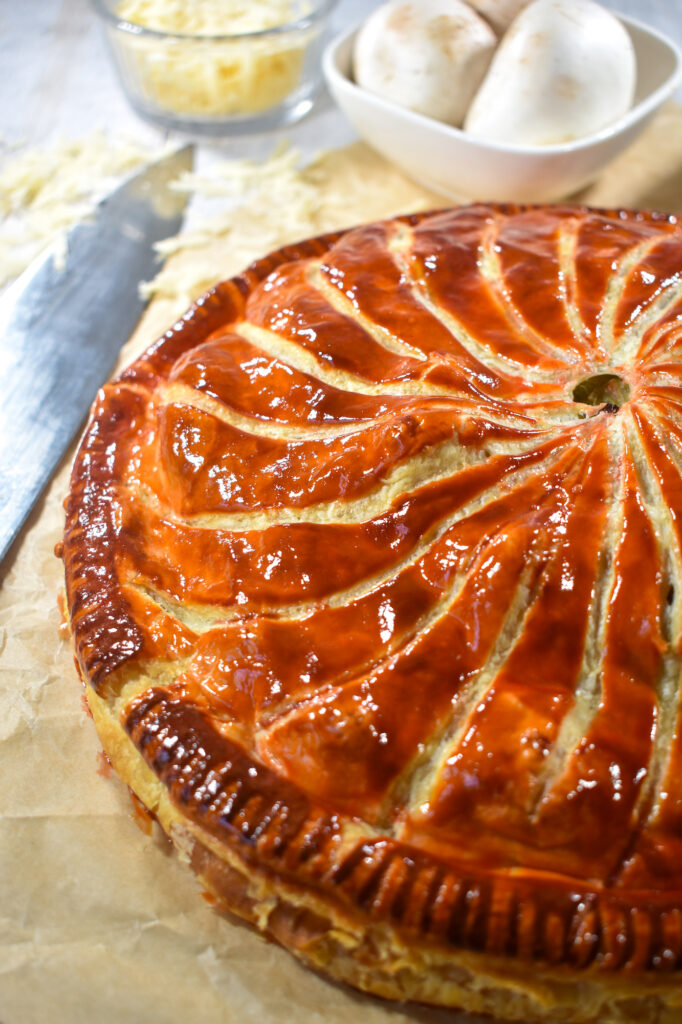 Pithivier with knife, mushrooms, and a bowl of cheese