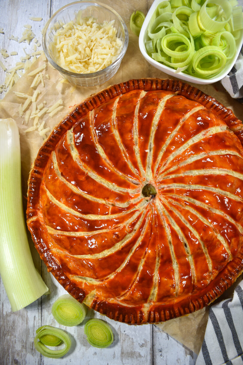 Whole pithivier with a bowl of leeks, cheese, and a whole leek