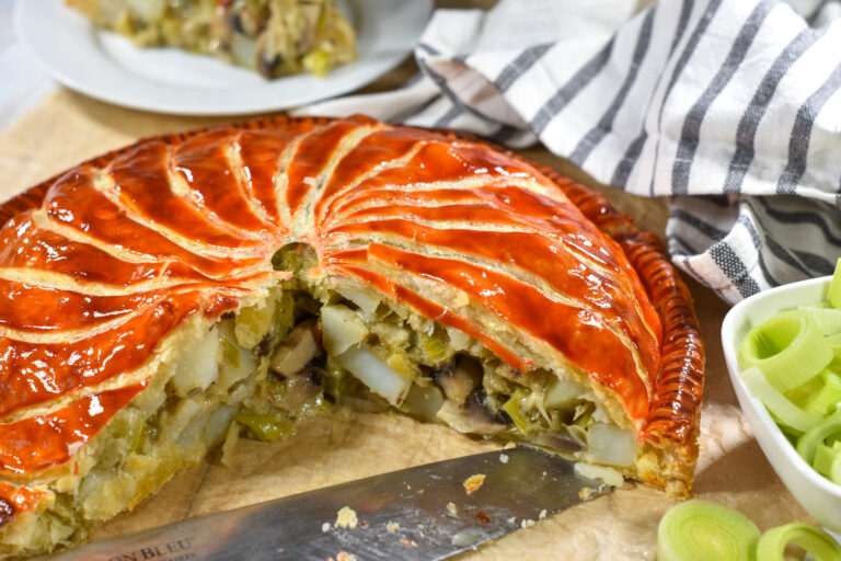 Horizontal shot of pithivier with slice missing, showing the leek and mushroom filling