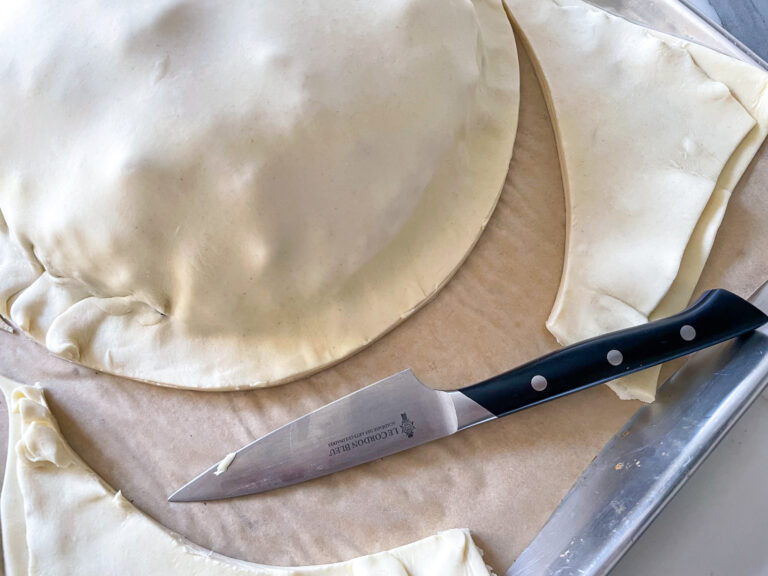 Unbaked pithiver and puff pastry scraps on tray with knife