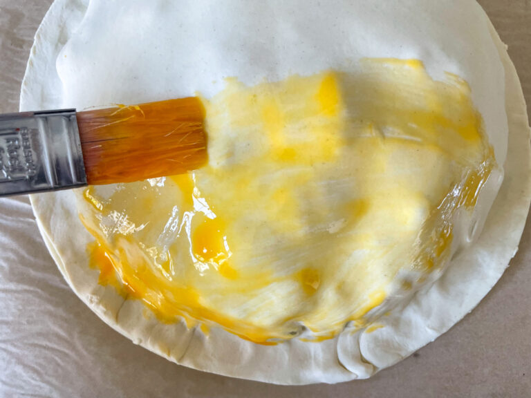 Brush applying egg wash to a pithivier