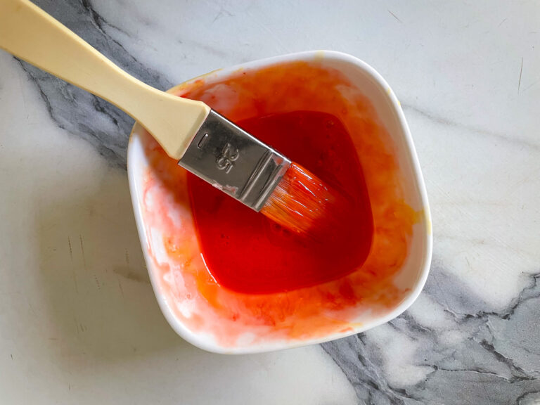 Bowl of red tinted egg wash and a brush