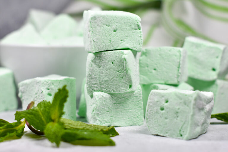 Stack of green pepperint marshmallows and fresh mint leaves