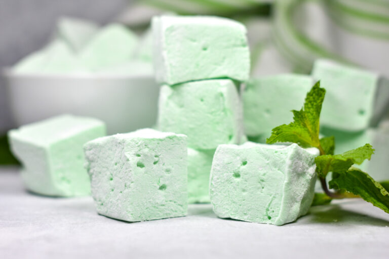 Stack of green pepperint marshmallows and fresh mint leaves
