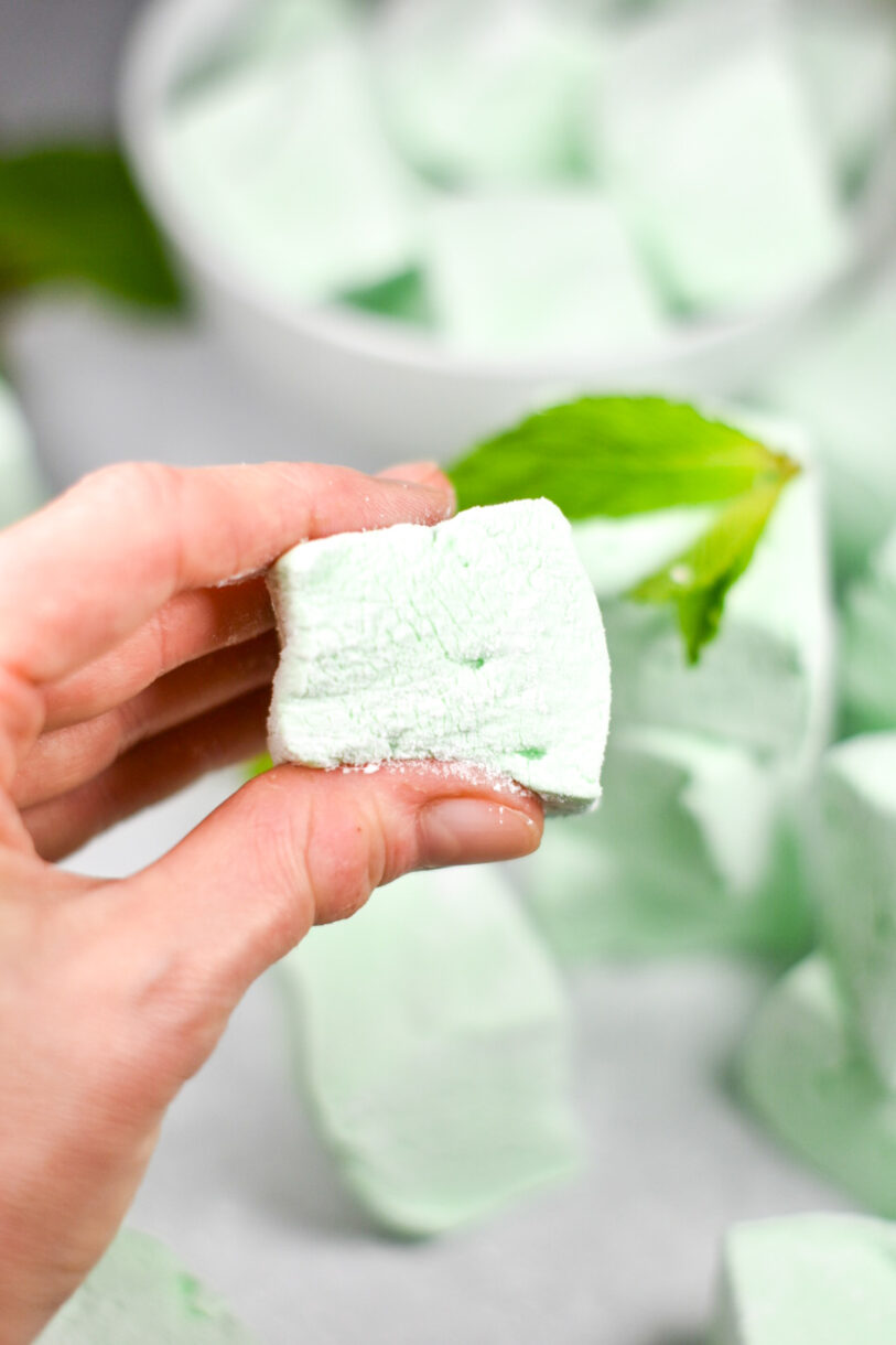 Hand holding a green marshmallow made from this peppermint marshmallow recipe