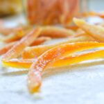 Homemade candied orange peels on white surface