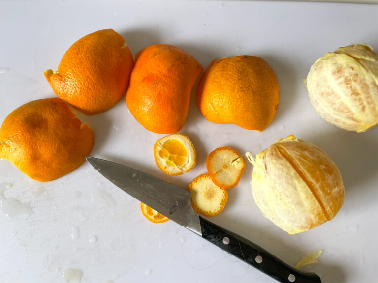 Oranges and peels on cutting board with knife
