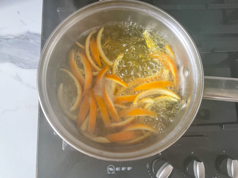 Orange peels in a metal saucepan bubbling on stovetop