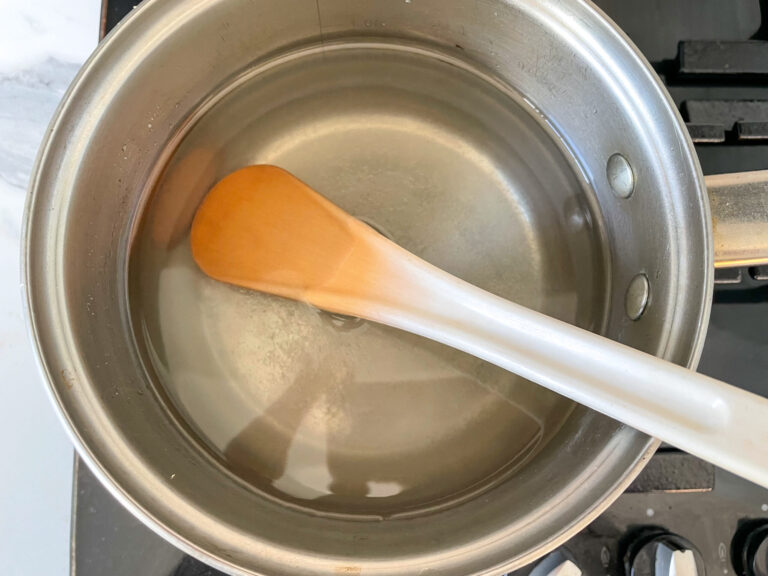 Sugar and water in saucepan with spoon
