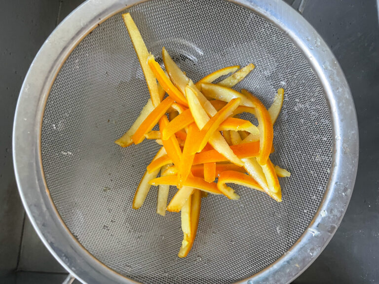 Candied orange peels in a mesh strainer