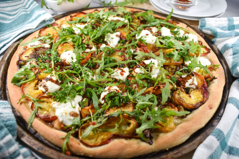 Peach and goat cheese pizza with arugula on top