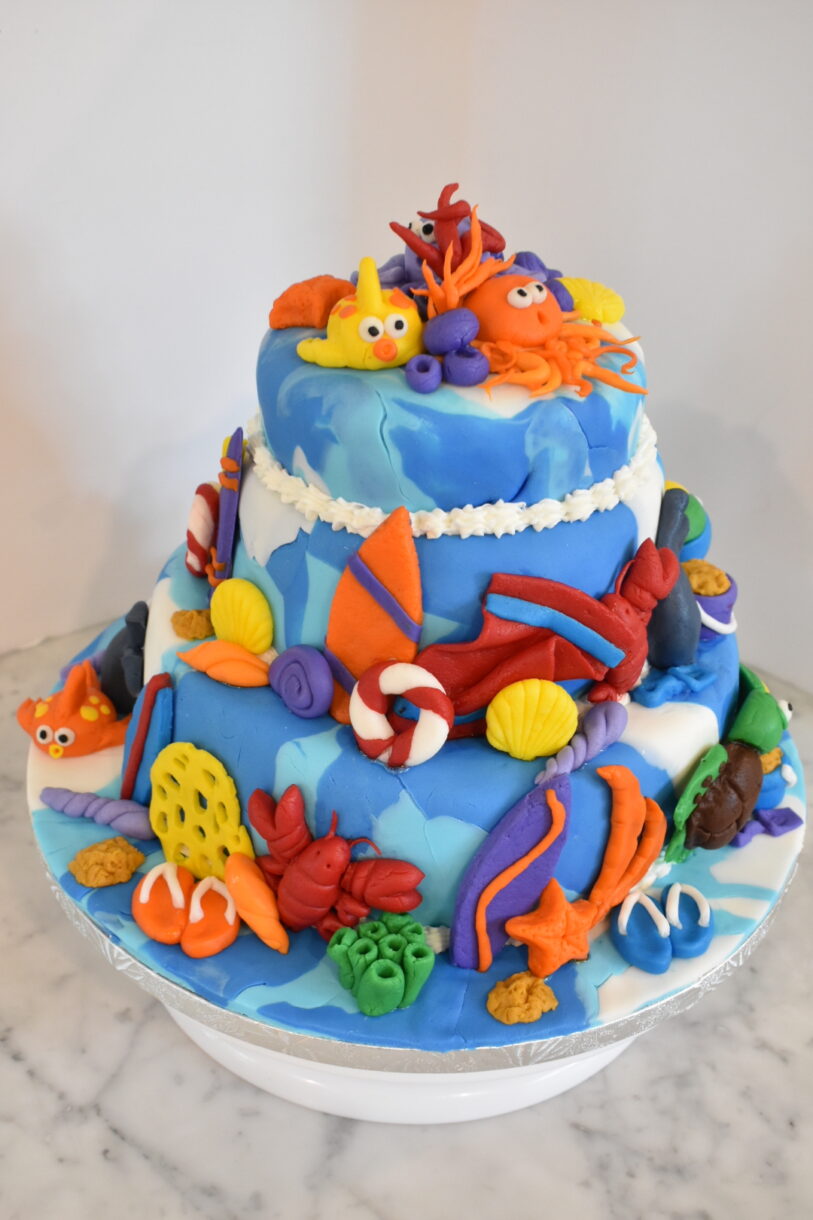 Beach themed cake decorated with fondant, on a marble countertop