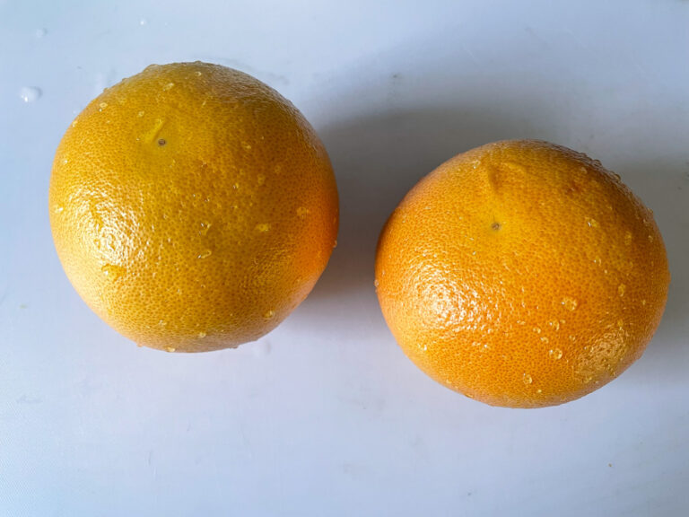 Two grapefruits on a white cutting board