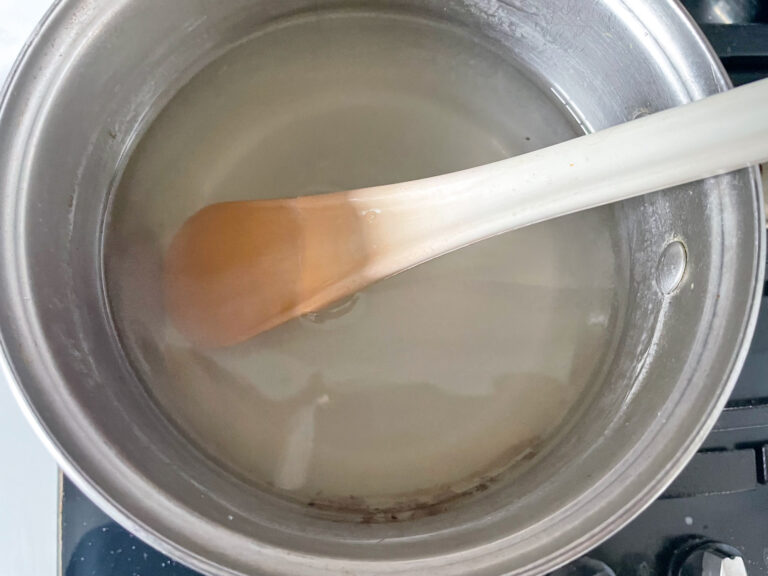 Sugar and water in saucepan with a spoon
