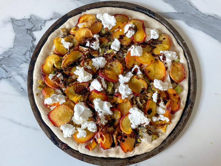 Peach and goat cheese pizza on marble countertop, before baking