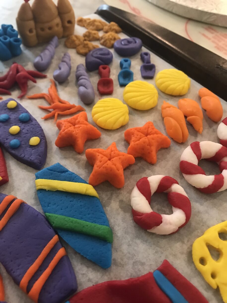 Seashells, starfish, surfboards, and other cake decorations made out of fondant