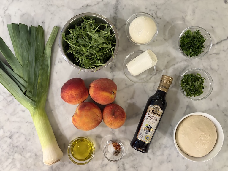 Peach and goat cheese pizza recipe ingredients on a marble surface