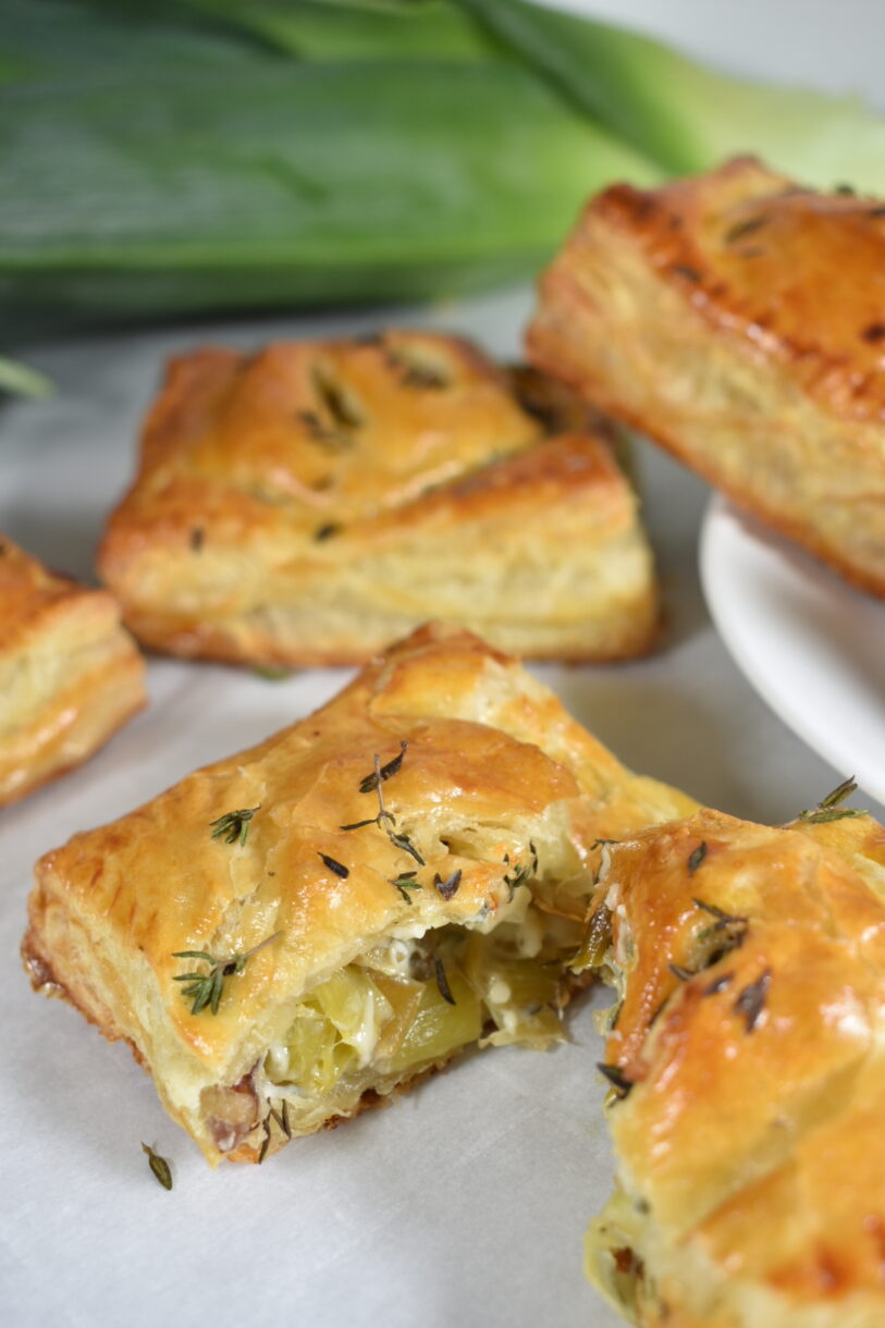 Flaky golden brown puff pastry hand pie, cut in half to reveal caramelized leek filling