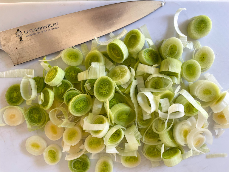 Sliced leeks and a knife on a cutting board