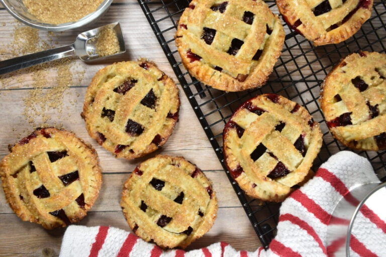 Cherry hand pies on a wire rack, and a spoonful of Demerara sugar and a tea towel