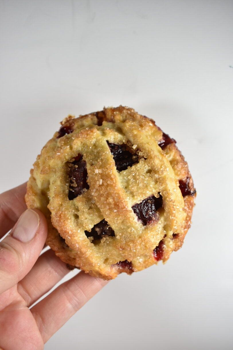 Hand holding a small cherry pie with lattice pastry top