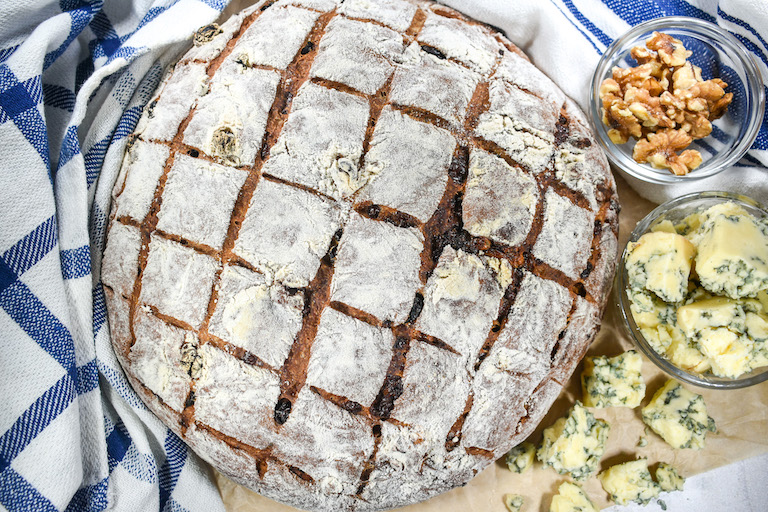 Gorgonzola bread arranged on a surface with walnuts, cheese, and tea towels