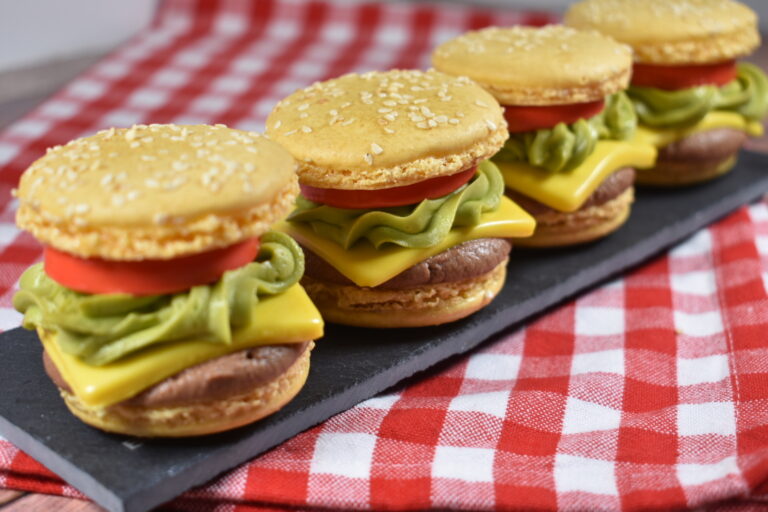 Four cheeseburger macarons arranged on a slate board