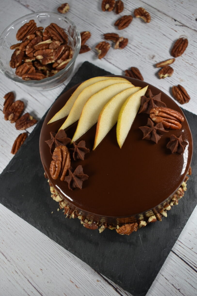 Autumn pear cake with chocolate mirror glacage, along with a bowl of pecans