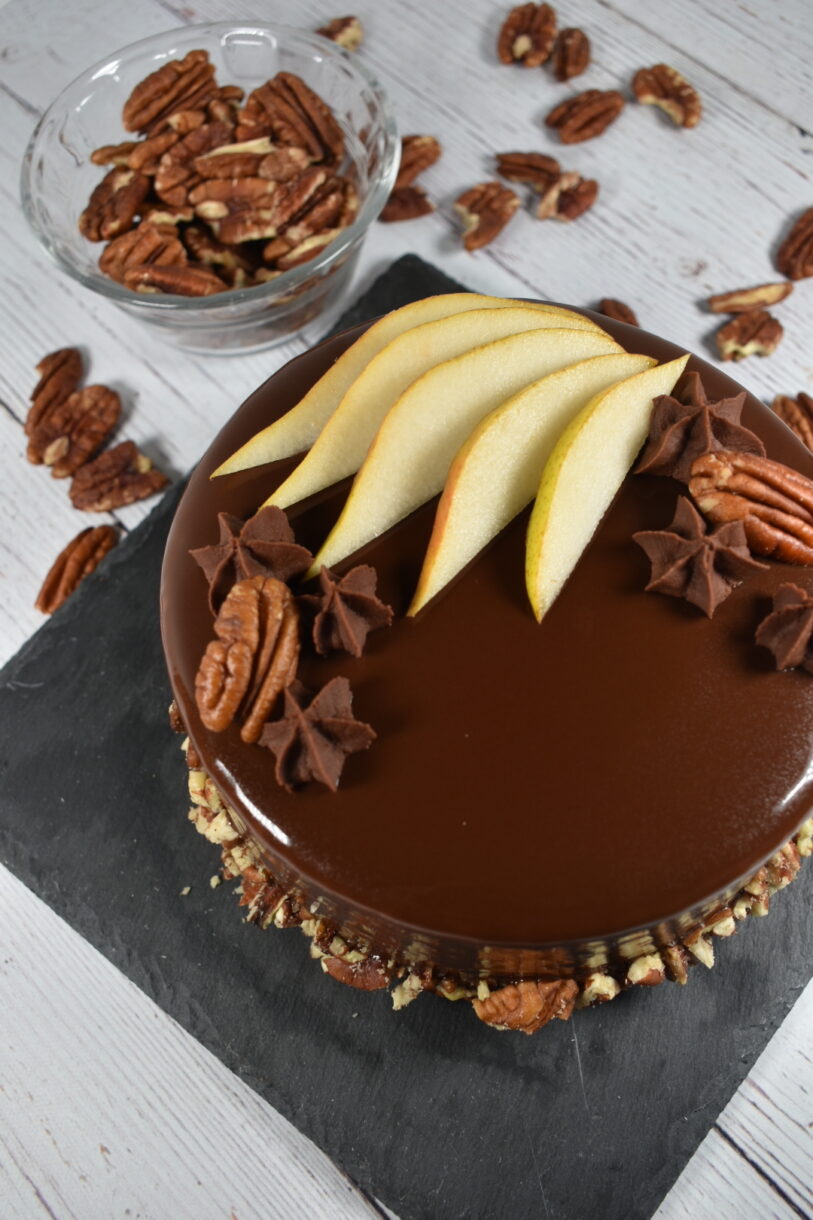 Autumn pear entremet on a slate board, surrounded by pecans