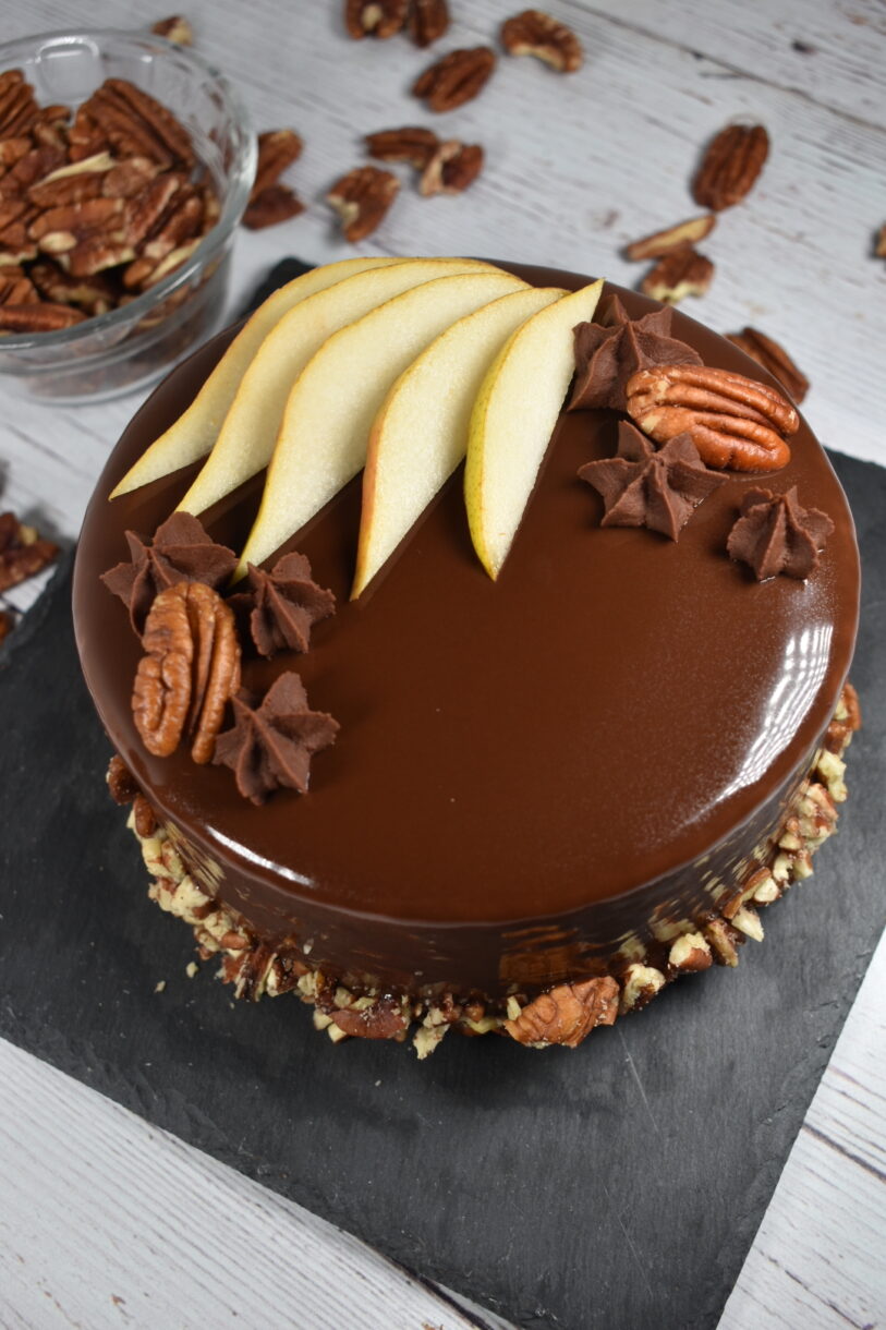 Autumn pear entremet on a slate board, surrounded by pecans, on a wood surface