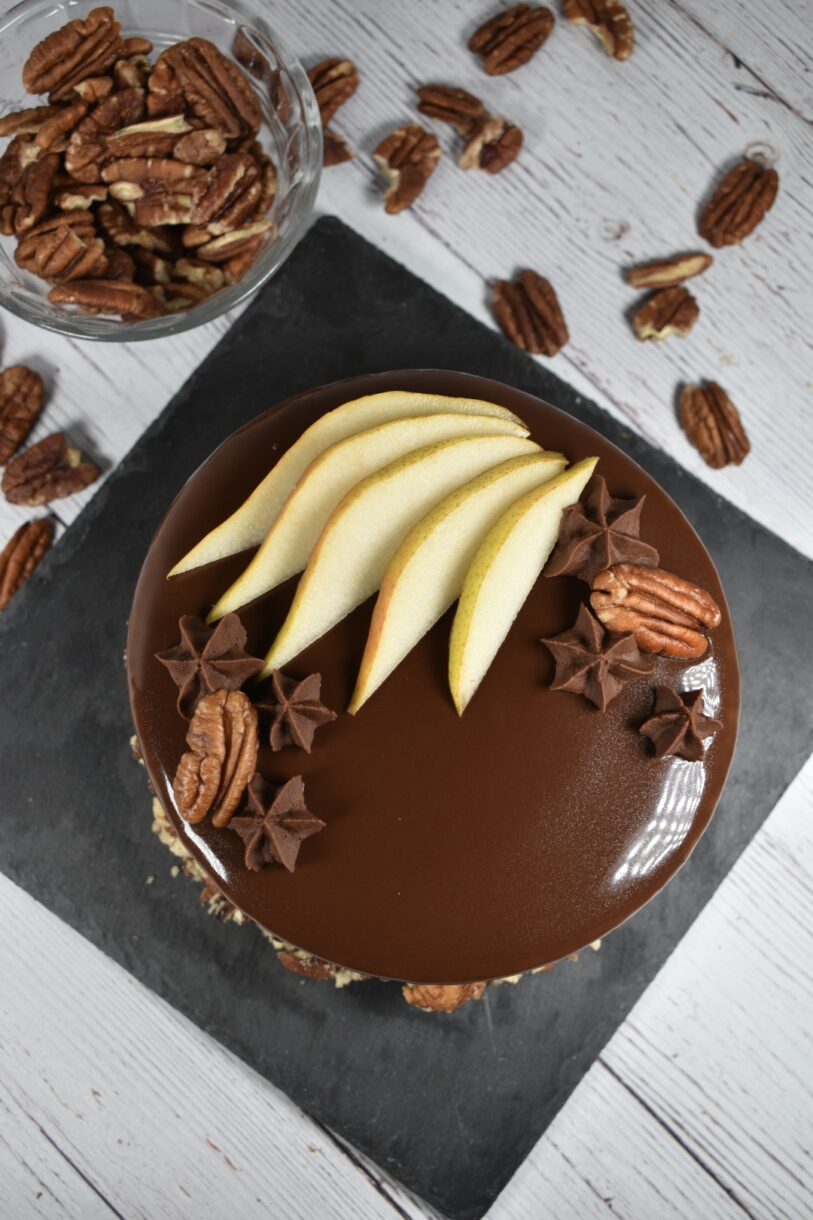 Autumn pear entremet on a slate board, surrounded by pecans and a chef's knife