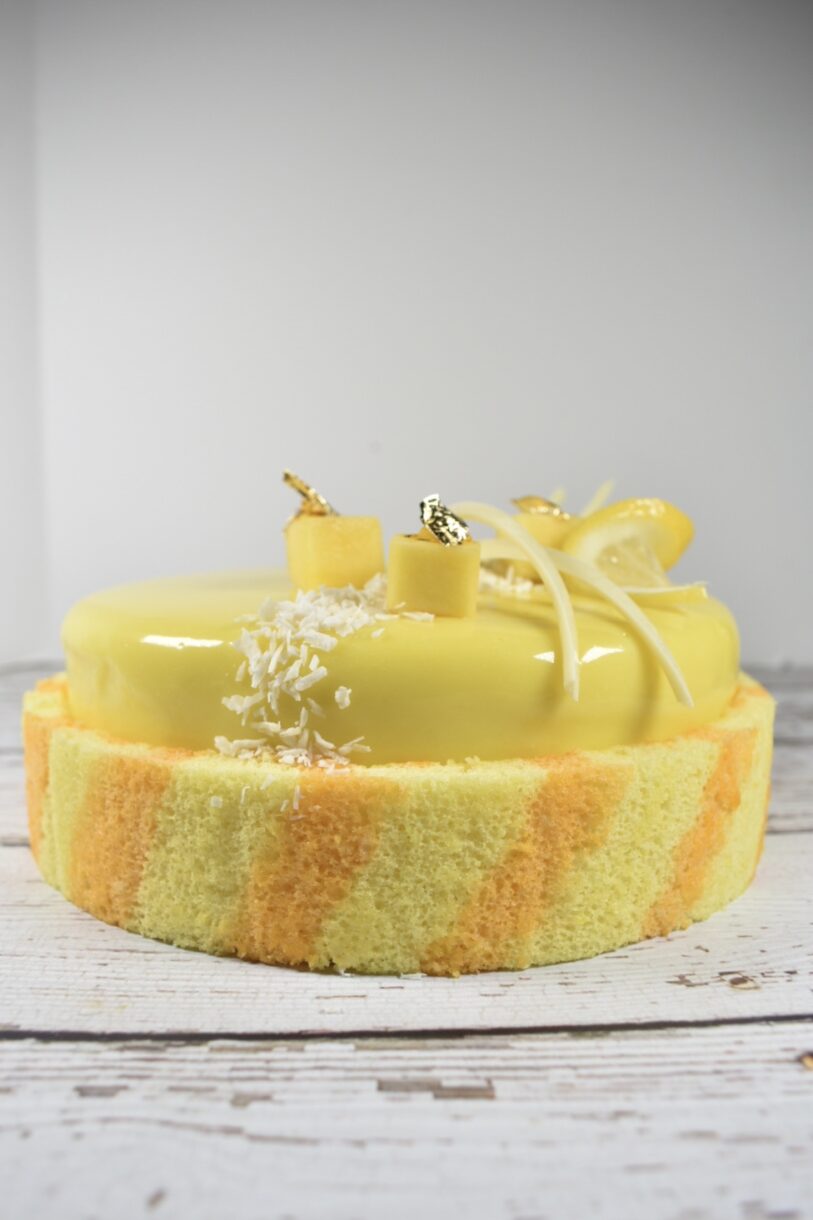 Front view of lemon entremet cake with striped sponge wrap