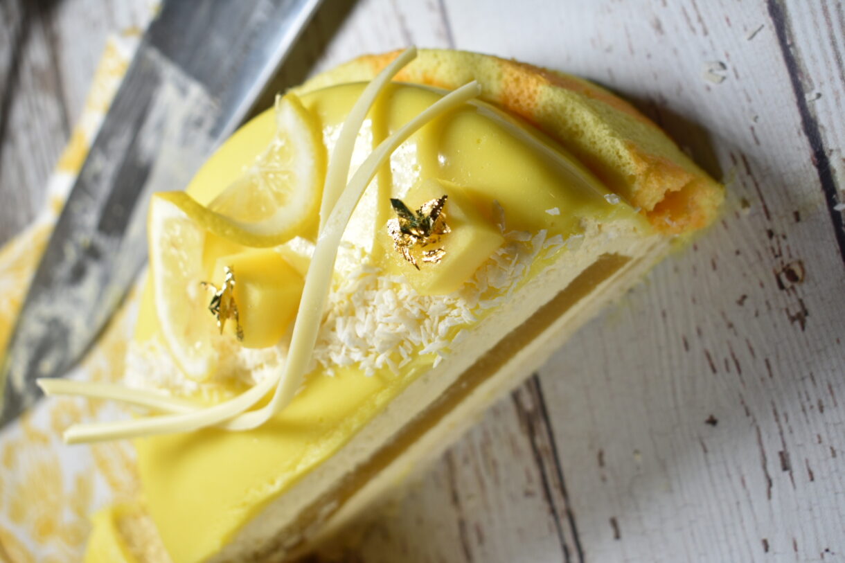 A slice of yellow lemon and white chocolate entremet cake showing the layers inside