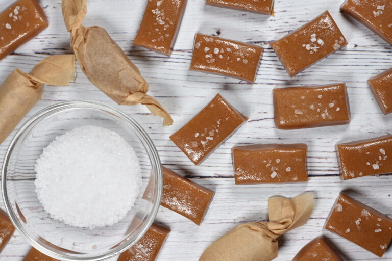 Cider caramels and a bowl of salt on a white background